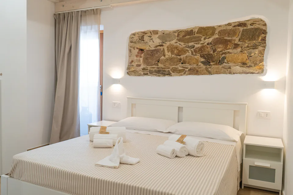 Letto matrimoniale e parete in pietra